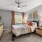  A bedroom with a bed, nightstand, and a ceiling fan.
