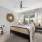  A bedroom with a bed, a bench, and a wall decoration.