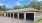  A building with a brown roof and black garage doors.