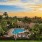  A building with a pool surrounded by palm trees.