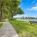  A bench sits on the grass beside a concrete walkway.
